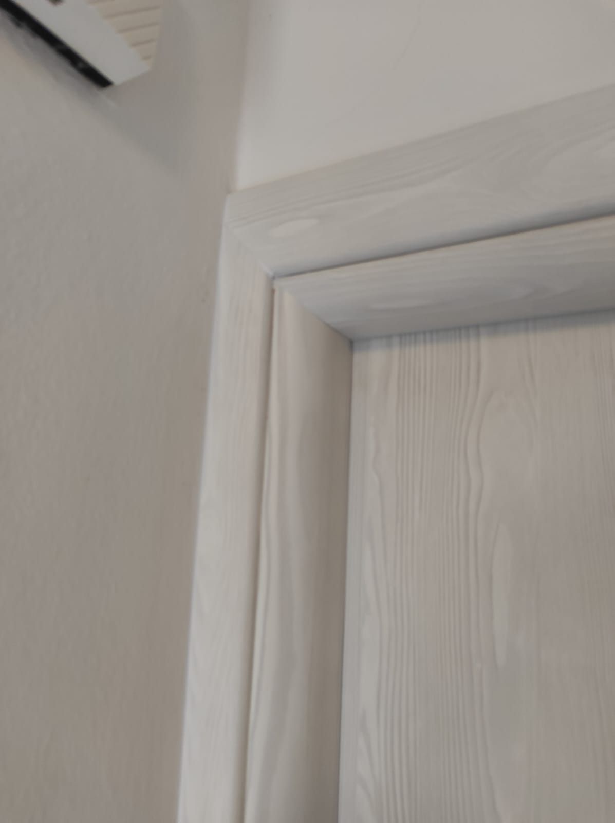 Un primo piano di una porta bianca con una cornice bianca in una stanza.