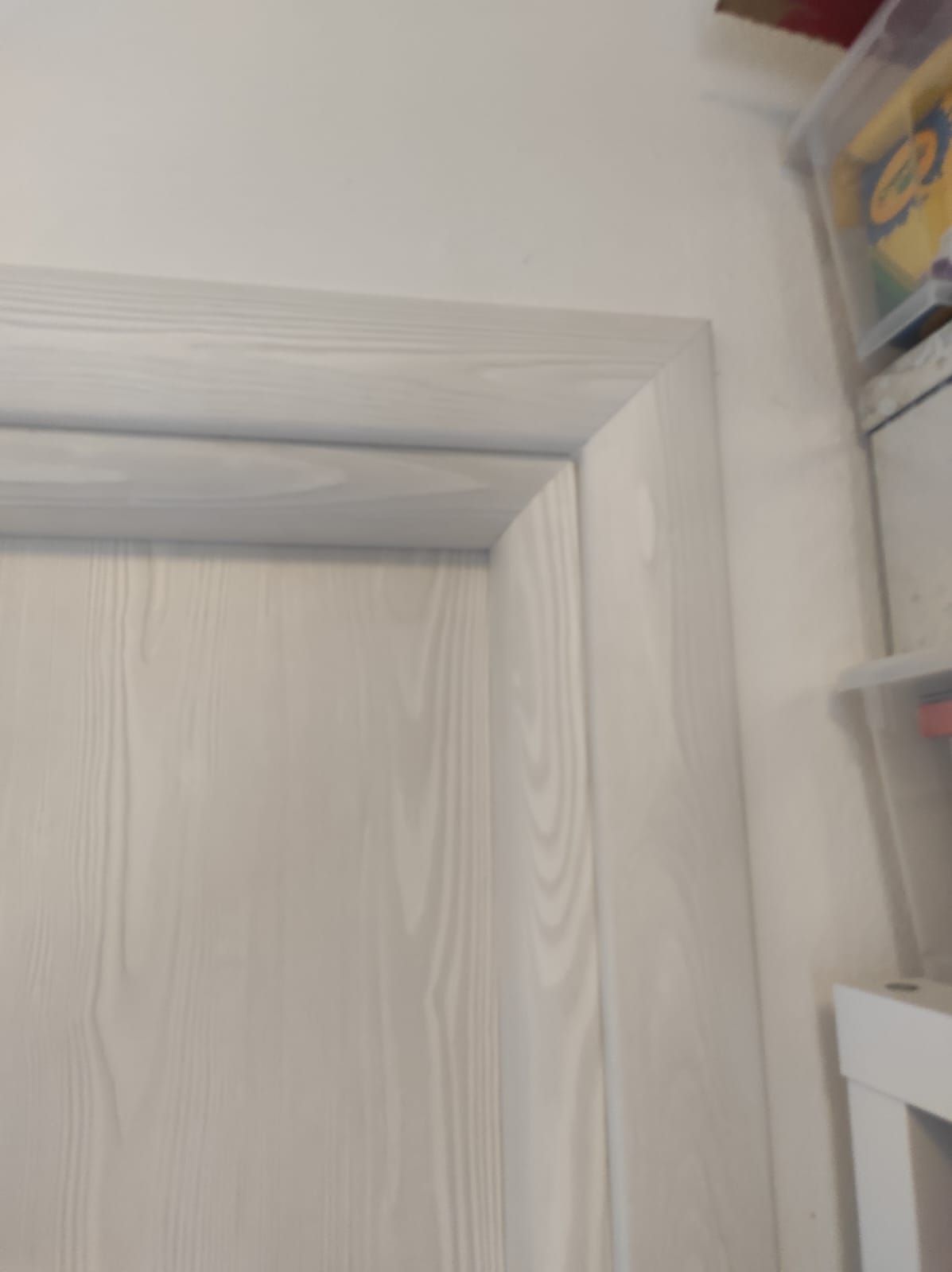 Un primo piano di una porta bianca con una rifinitura bianca in una stanza.