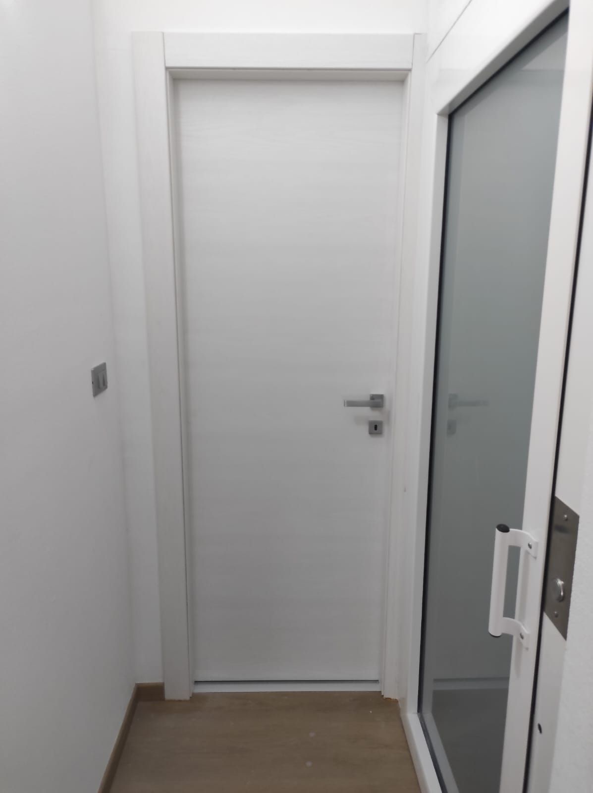 Una porta bianca con una porta a vetri in un corridoio.