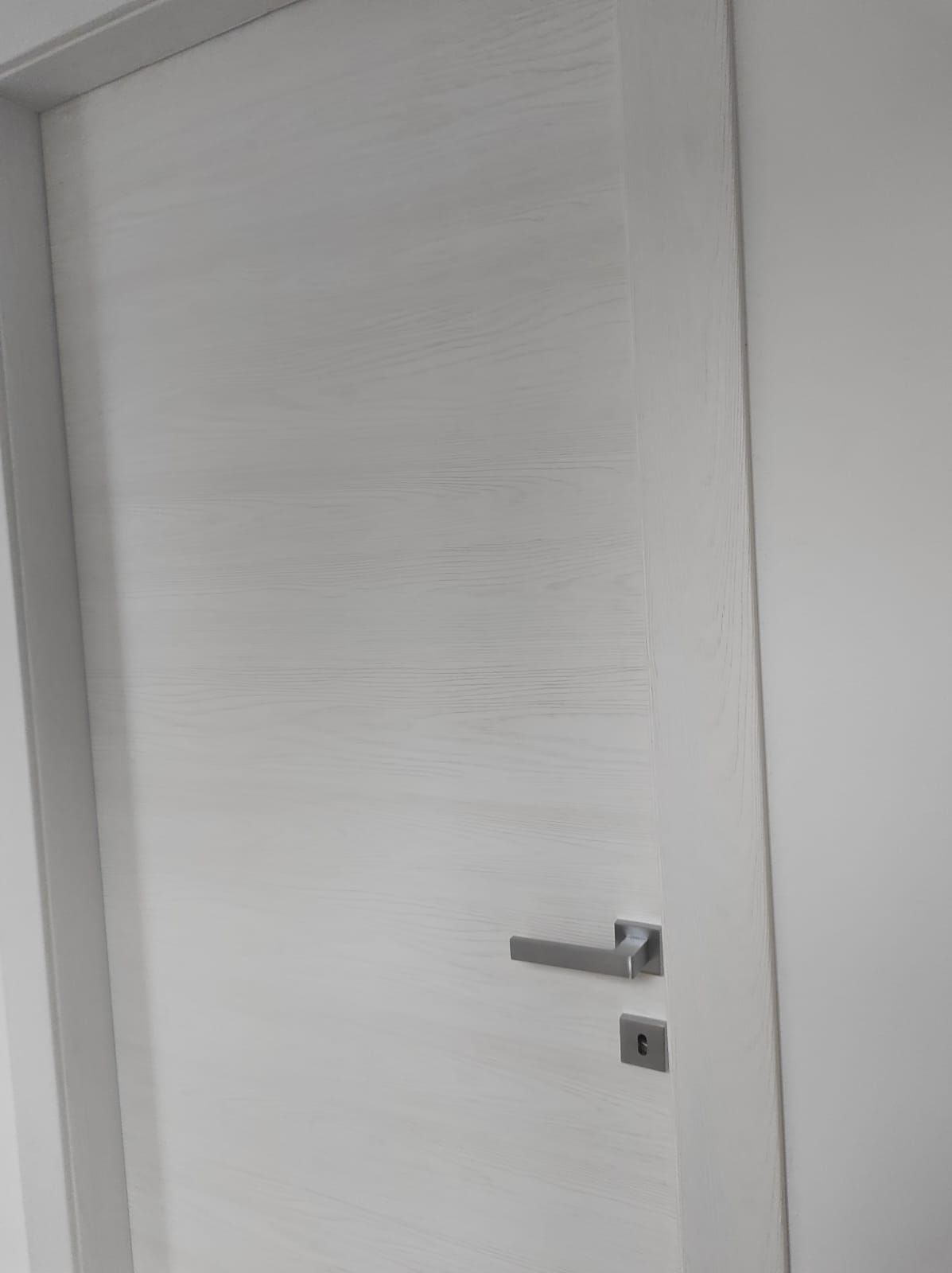 Un primo piano di una porta bianca con una maniglia argentata.