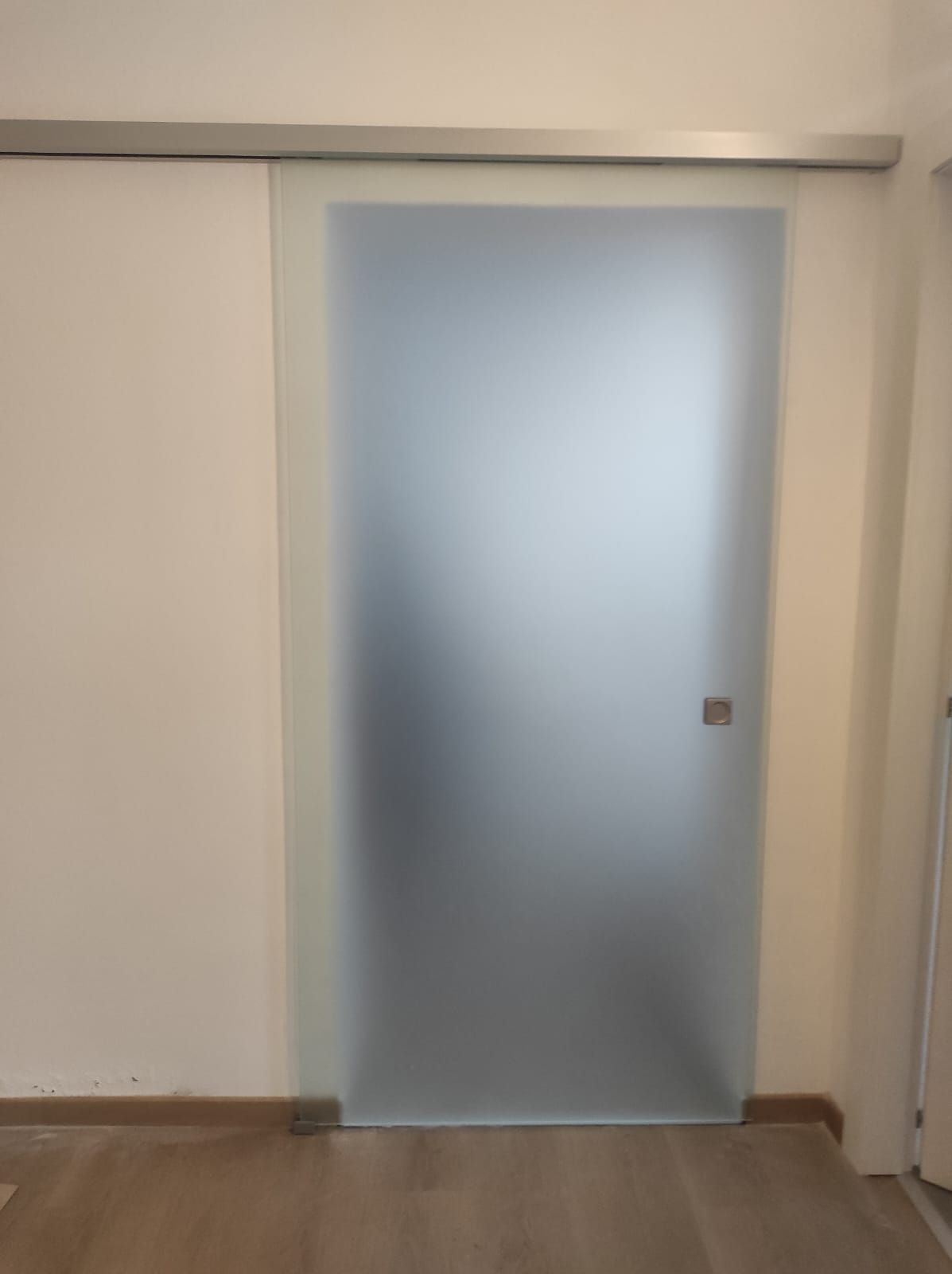 Una porta scorrevole in vetro in una stanza con una parete bianca.