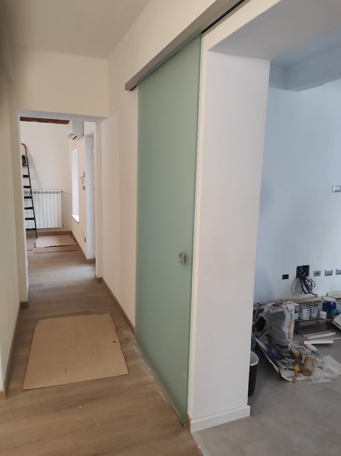 Un corridoio con una porta scorrevole in vetro tra due stanze