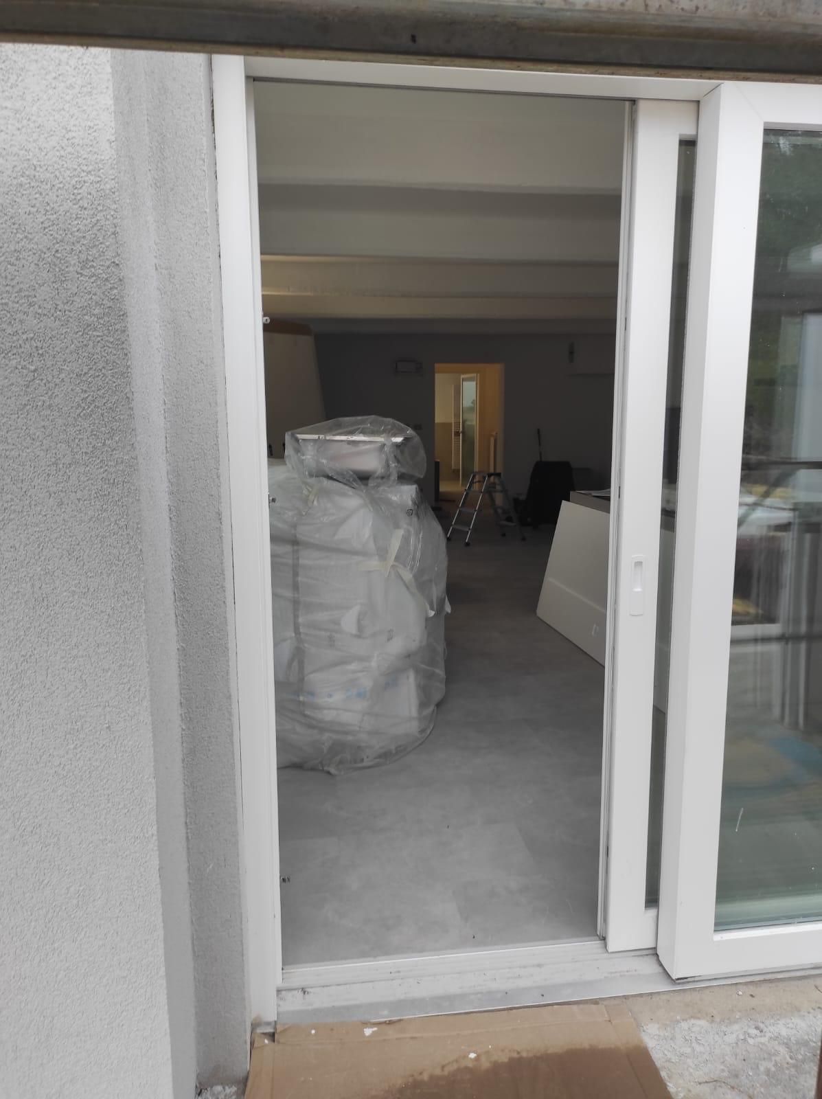 Una porta scorrevole in vetro bianco è aperta su una stanza.