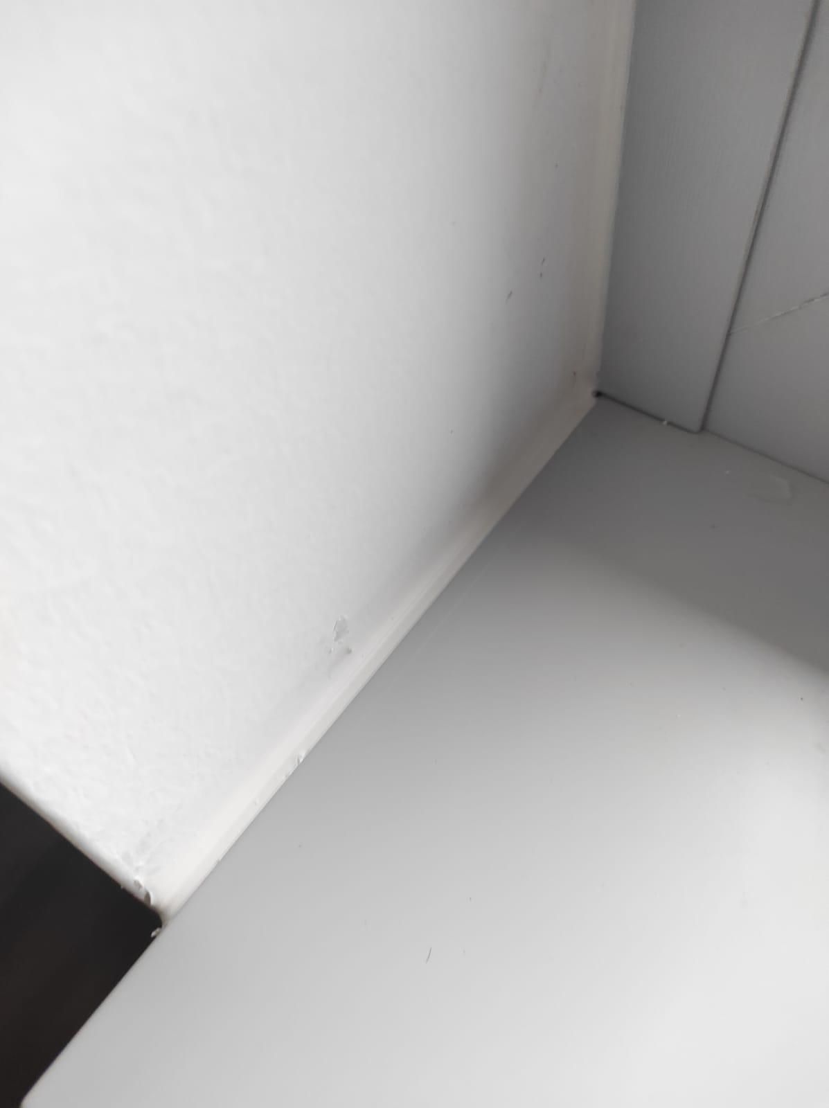 Un angolo di una stanza con una parete bianca e un pavimento bianco.