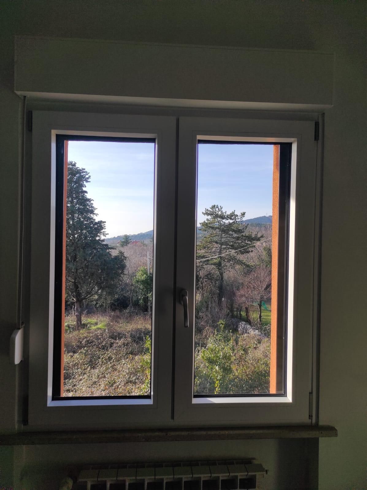 Una finestra con vista sugli alberi e sulle montagne