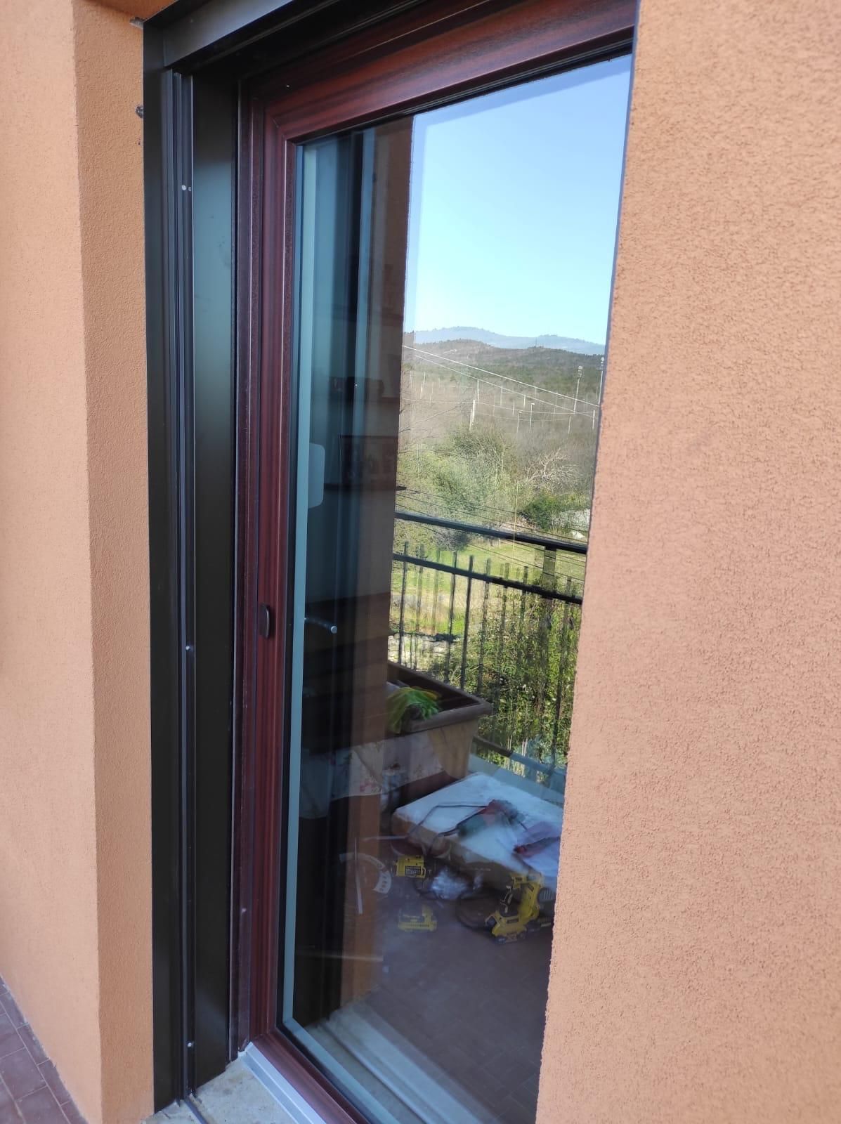 Una porta scorrevole in vetro si apre su un balcone.