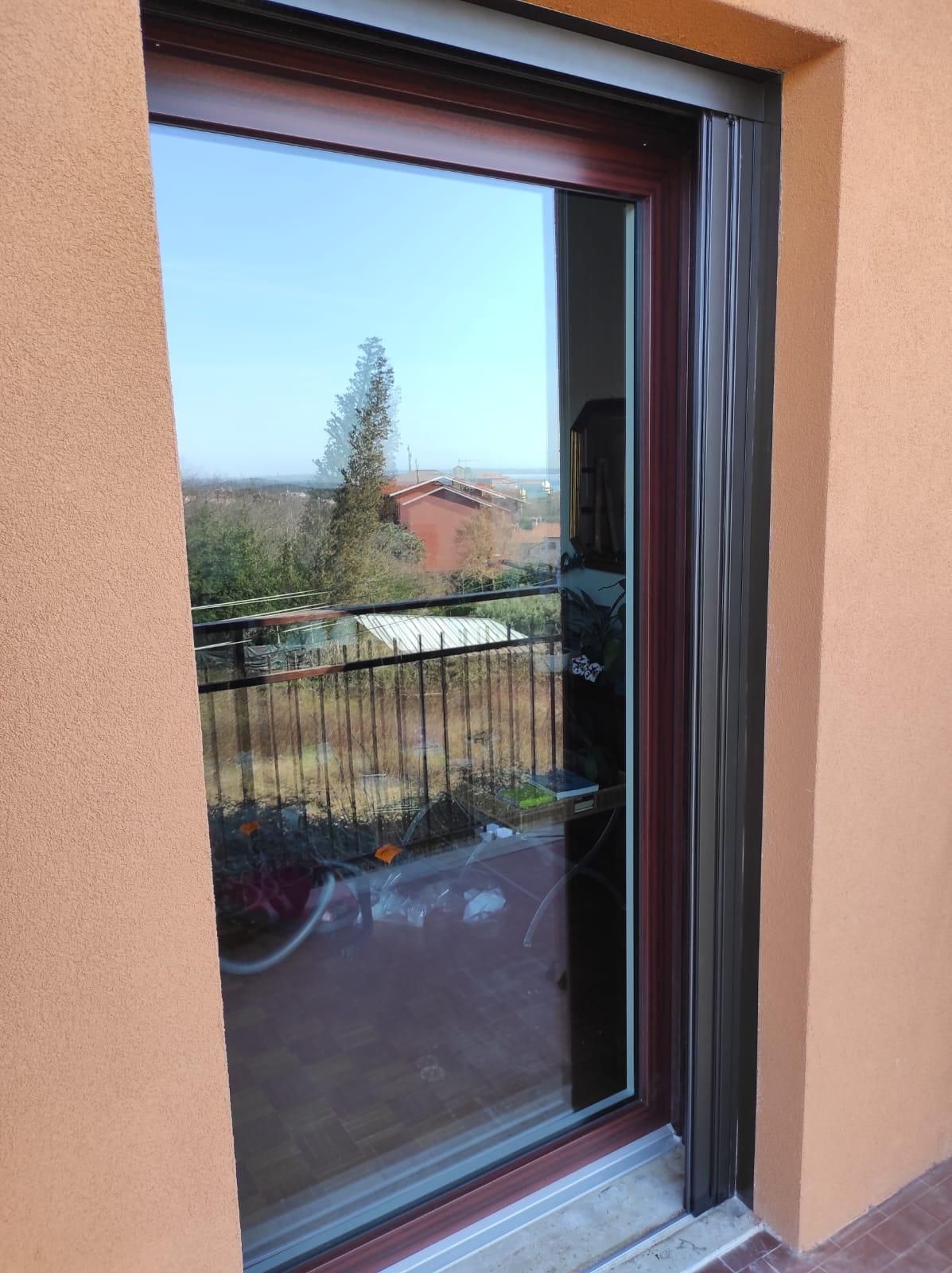 Una finestra con vista su un balcone si trova su un edificio.