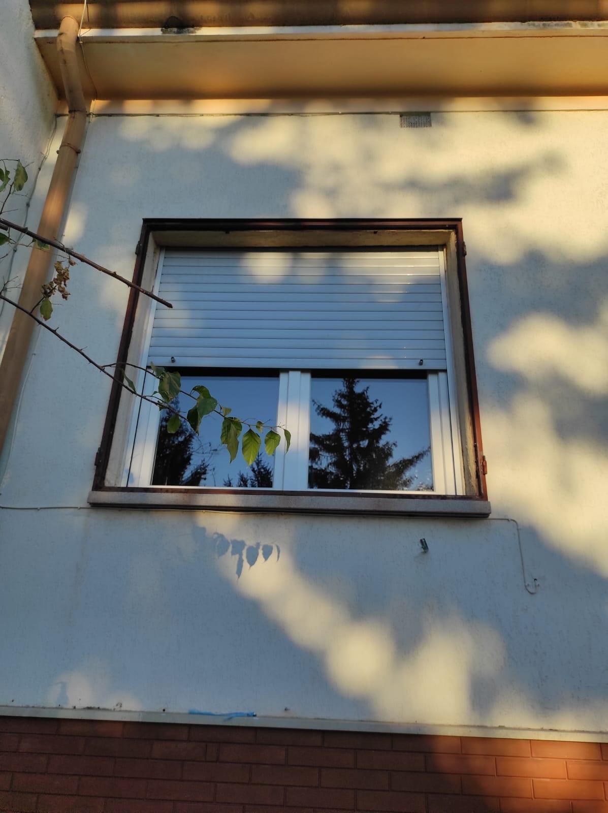 Una finestra con una persiana si trova sul lato di un edificio.