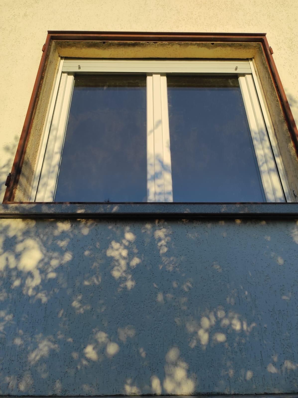 Una finestra sul lato di un edificio con un cielo azzurro dietro