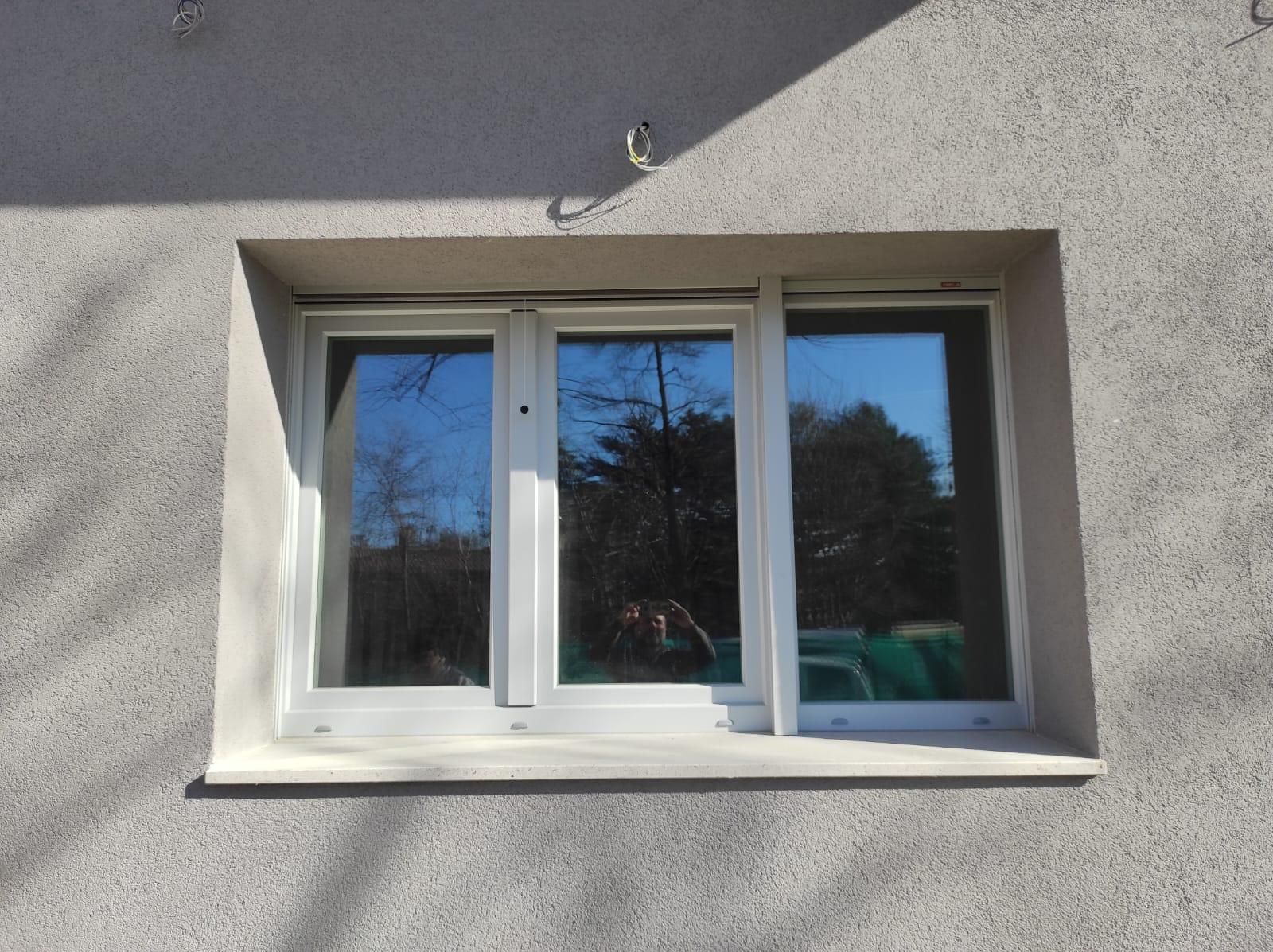 Una finestra sul lato di un edificio con un riflesso di alberi