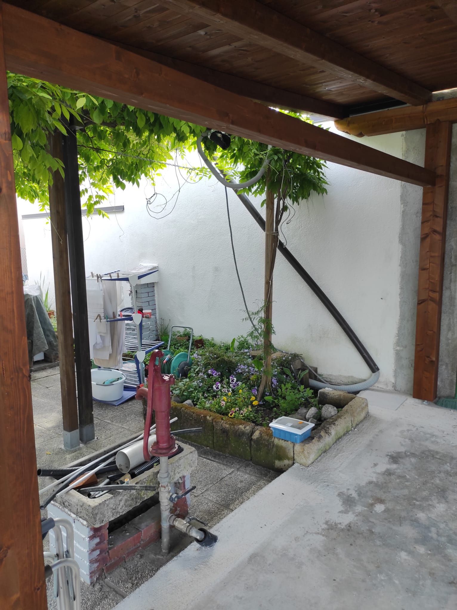 Un patio con tetto in legno e giardino sullo sfondo.