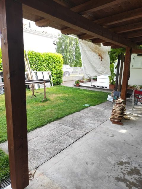 Un patio con tetto in legno e prato sullo sfondo