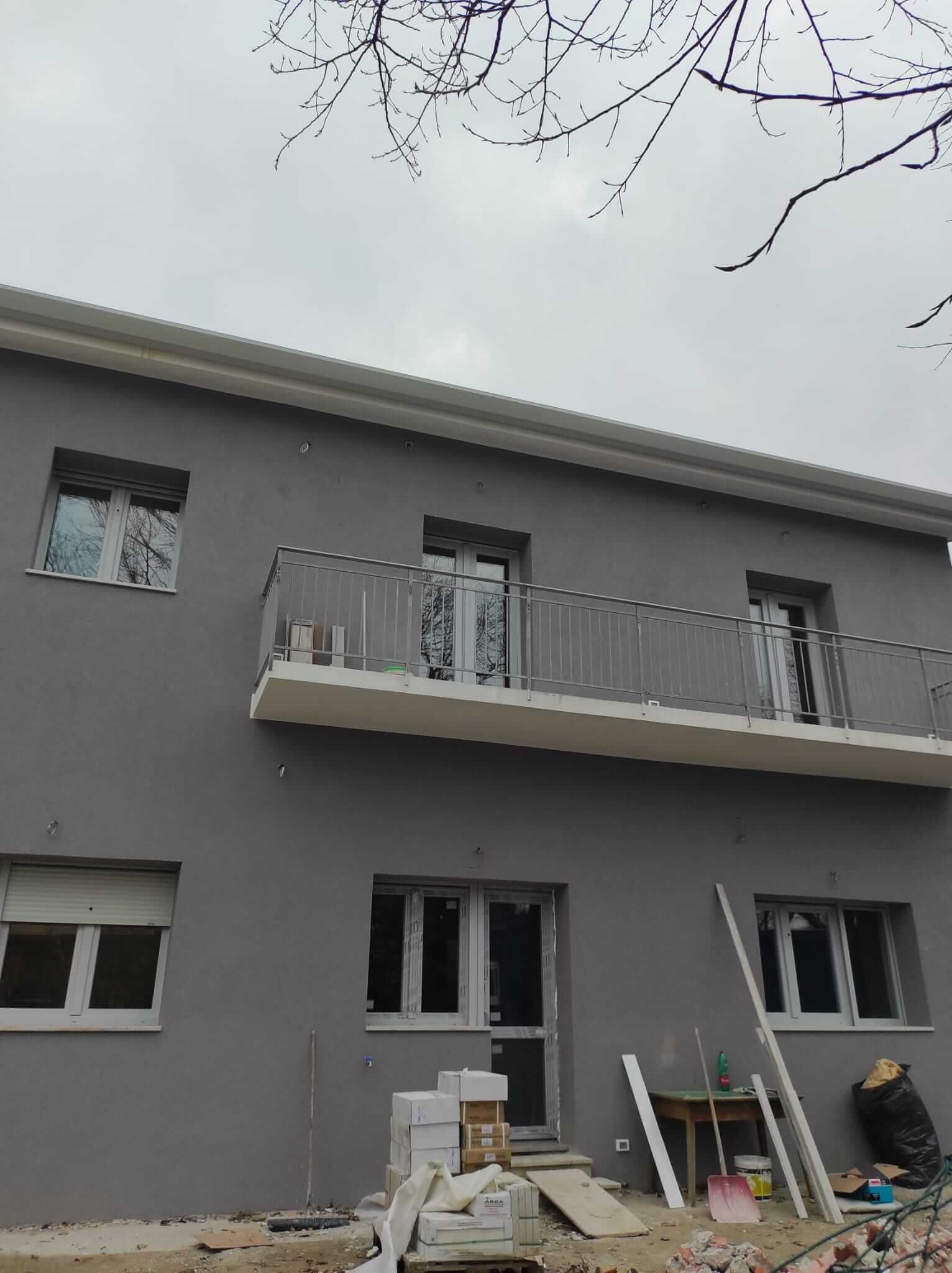 Un edificio in costruzione con un balcone e molte finestre.
