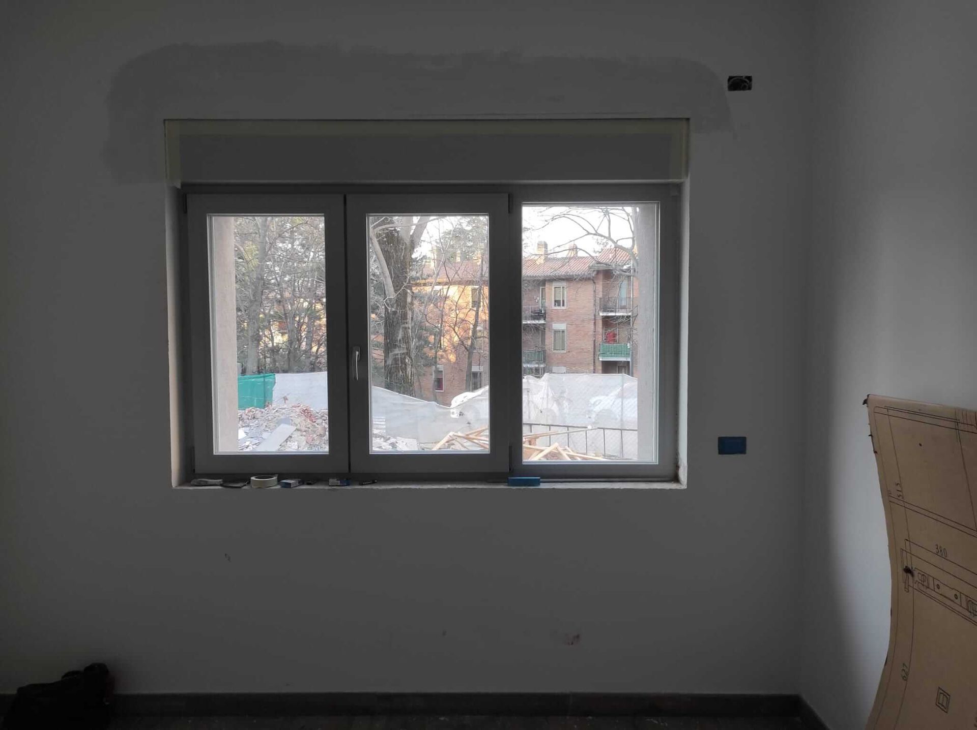 Una stanza vuota con una grande finestra e una scatola di cartone sul pavimento