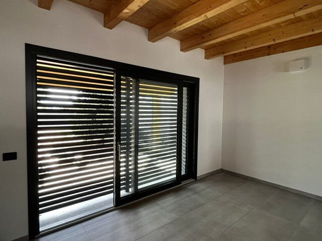 Una stanza vuota con una porta scorrevole in vetro e persiane.