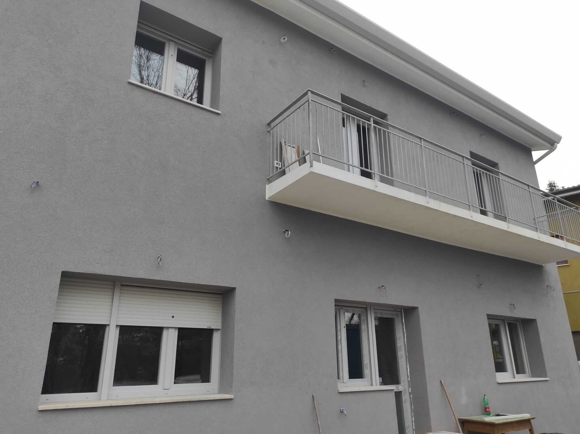 Un edificio grigio con un balcone e finestre bianche