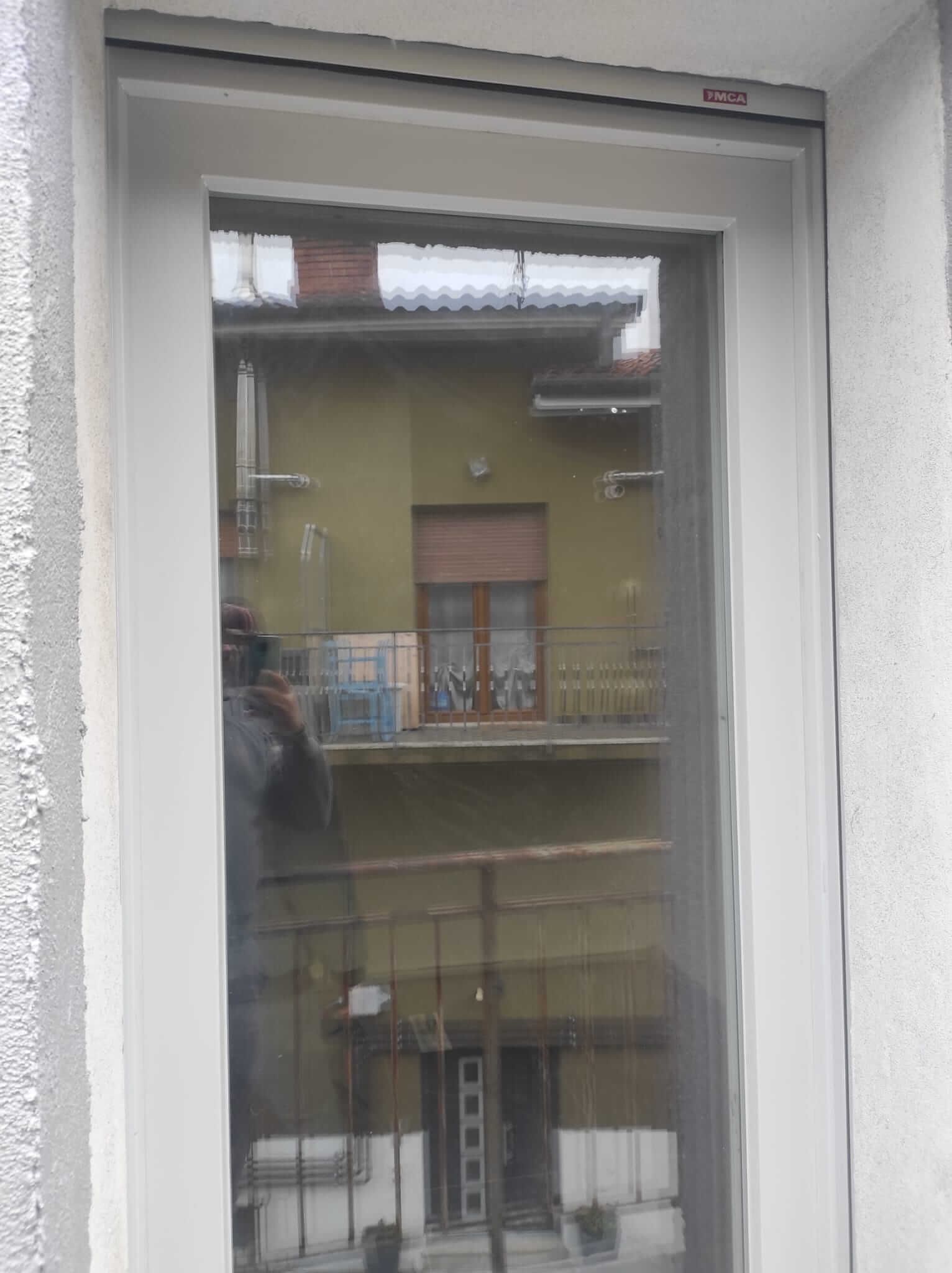 Una persona sta scattando una foto di un balcone attraverso una finestra.
