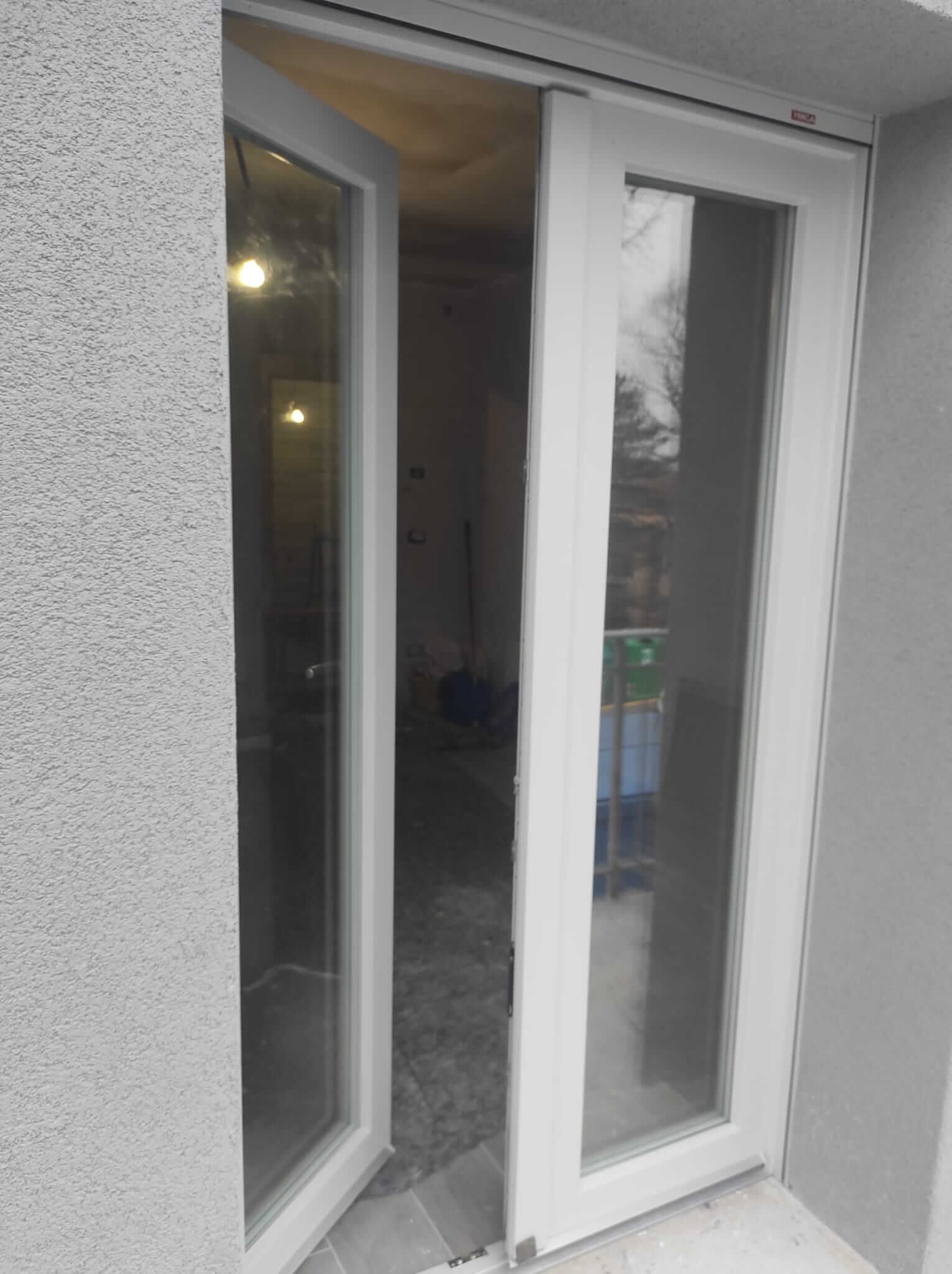 Una porta scorrevole in vetro bianco è aperta su una stanza.