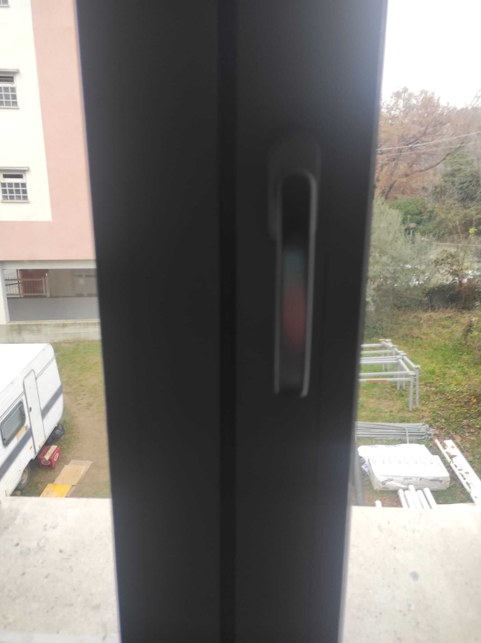 Un primo piano di una finestra con maniglia e vista di un edificio.