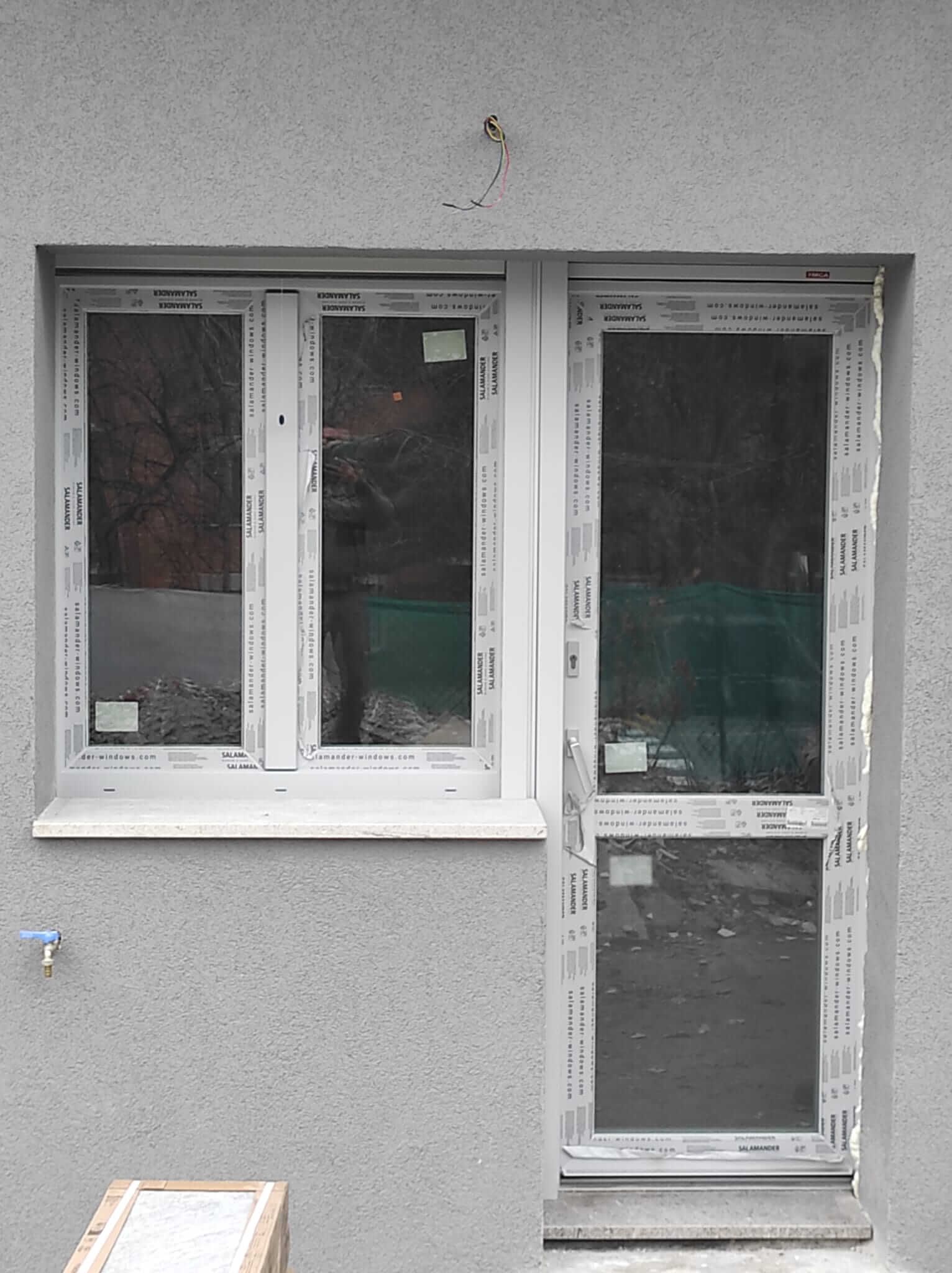 Un muro grigio con una finestra bianca e una porta