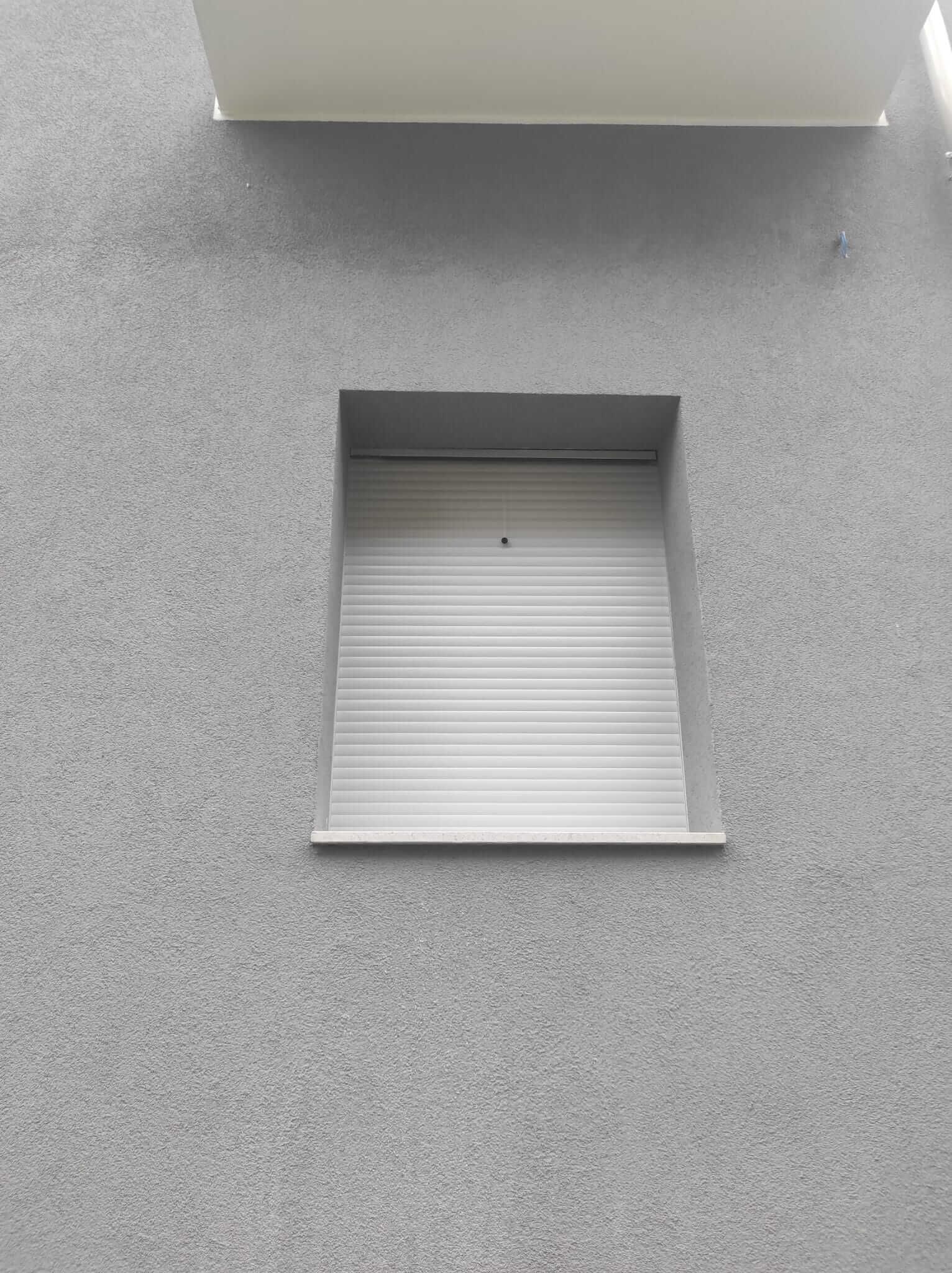 Una finestra con tapparella sul lato di un edificio.