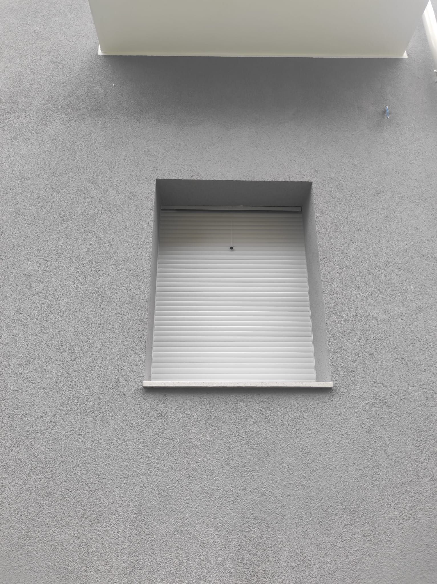 Una finestra con tapparella sul lato di un edificio.