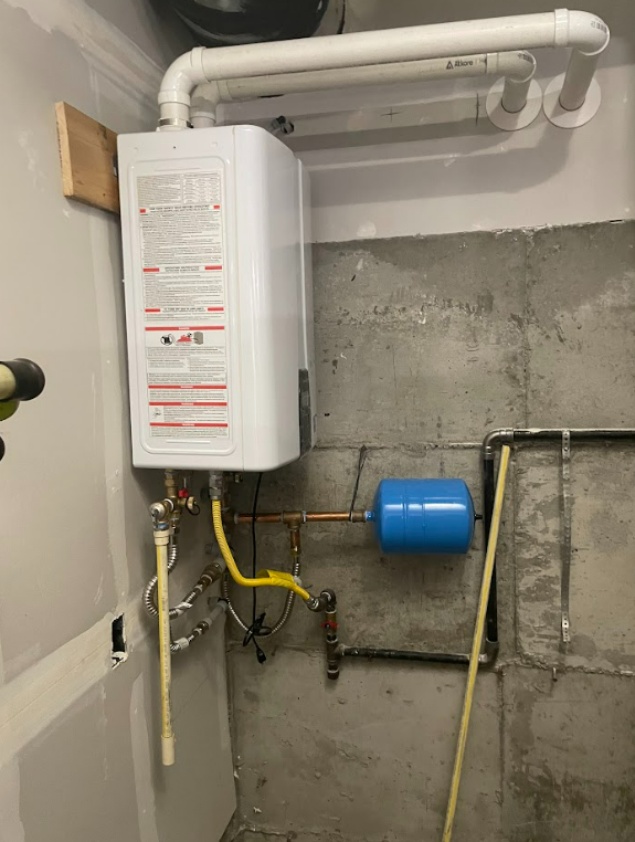 A white water heater is hanging on a wall next to a blue tank.