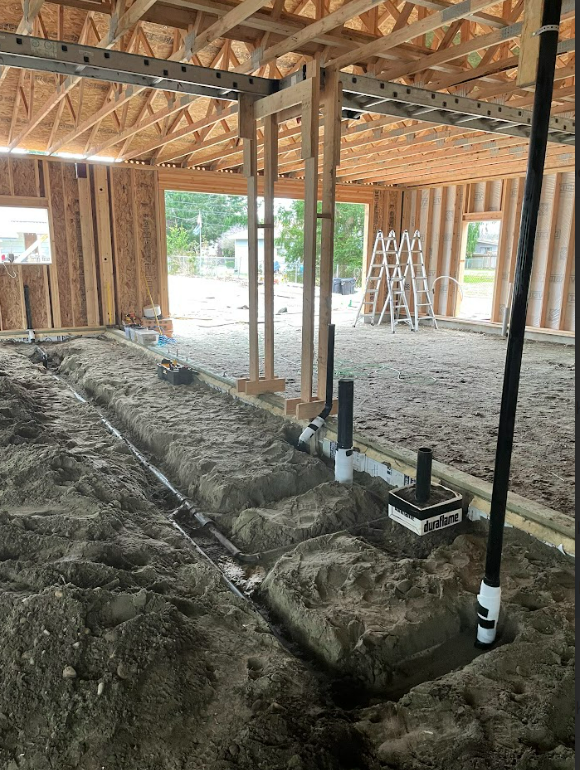 A house under construction with a lot of pipes in the dirt by royal flush plumbing in tacoma.