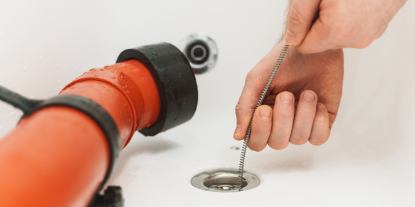 Drain Cleaning - A plumber snaking a bathtub drain