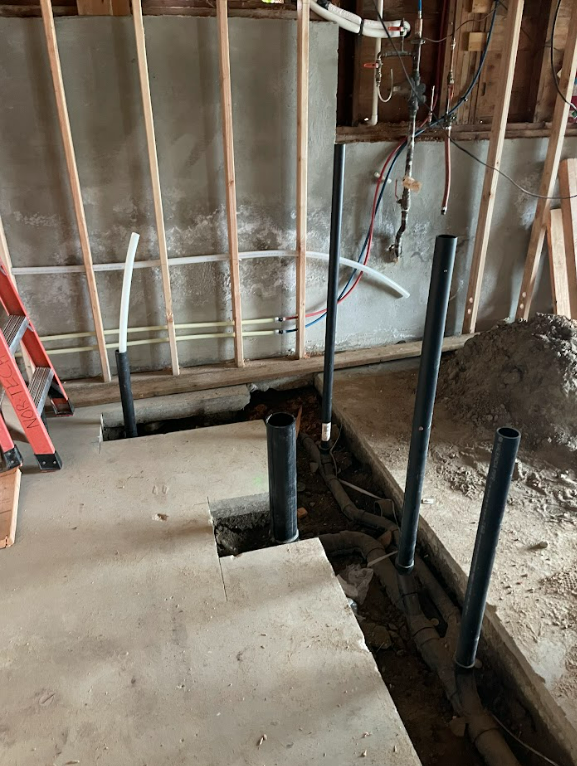 A room under construction with a ladder and pipes by royal flush plumbing in tacoma.