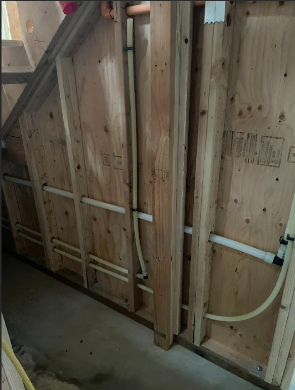 A wooden wall with a few pipes going through it