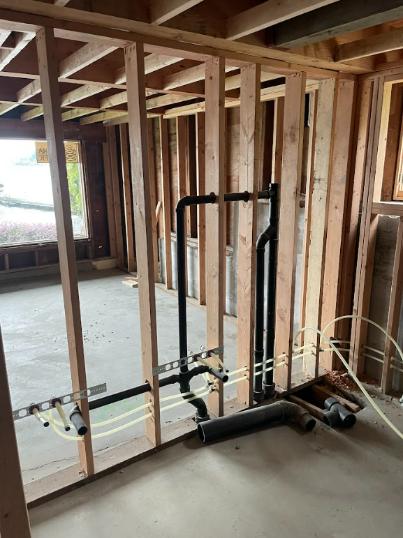 A room in a house under construction with pipes and wires.