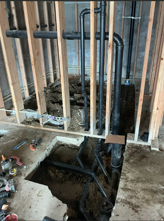 A room with a hole in the floor and pipes coming out of it.