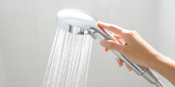 Bathroom Fixtures - Someone holding a running shower head