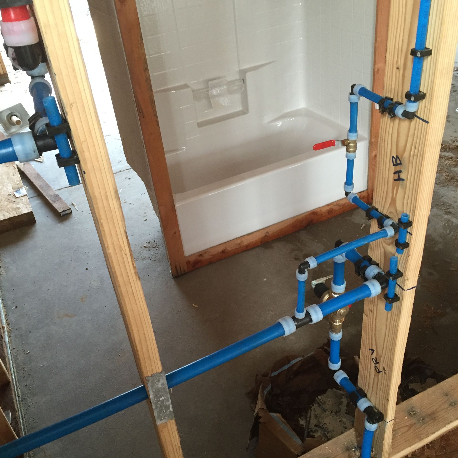 A bathroom with blue pipes and a bathtub with the letter h on the wall