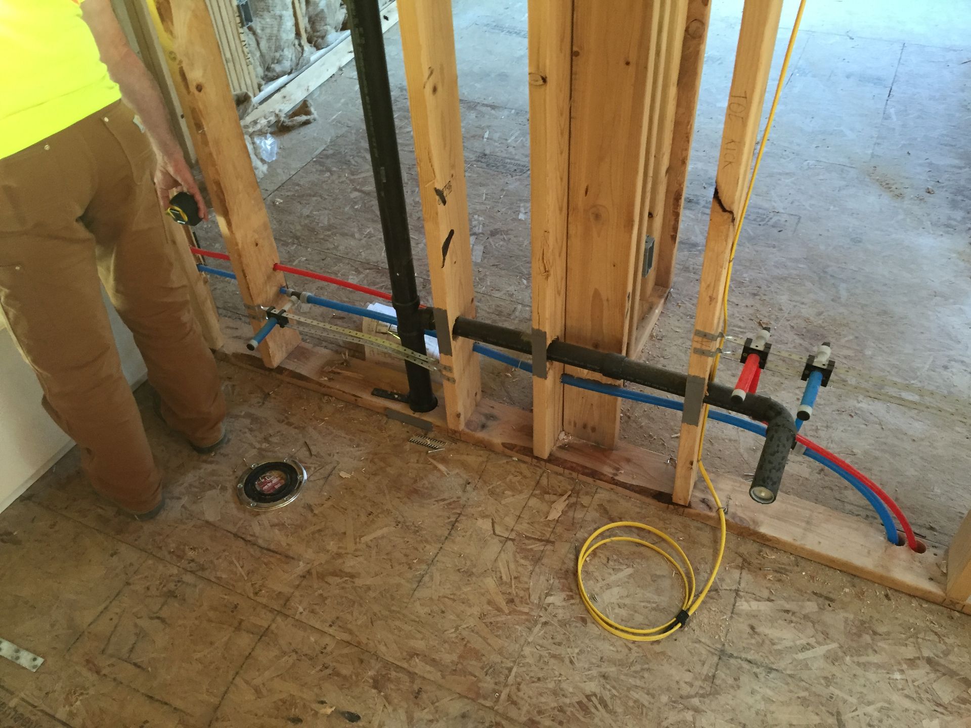 A person is measuring a pipe in a room with a tape measure.