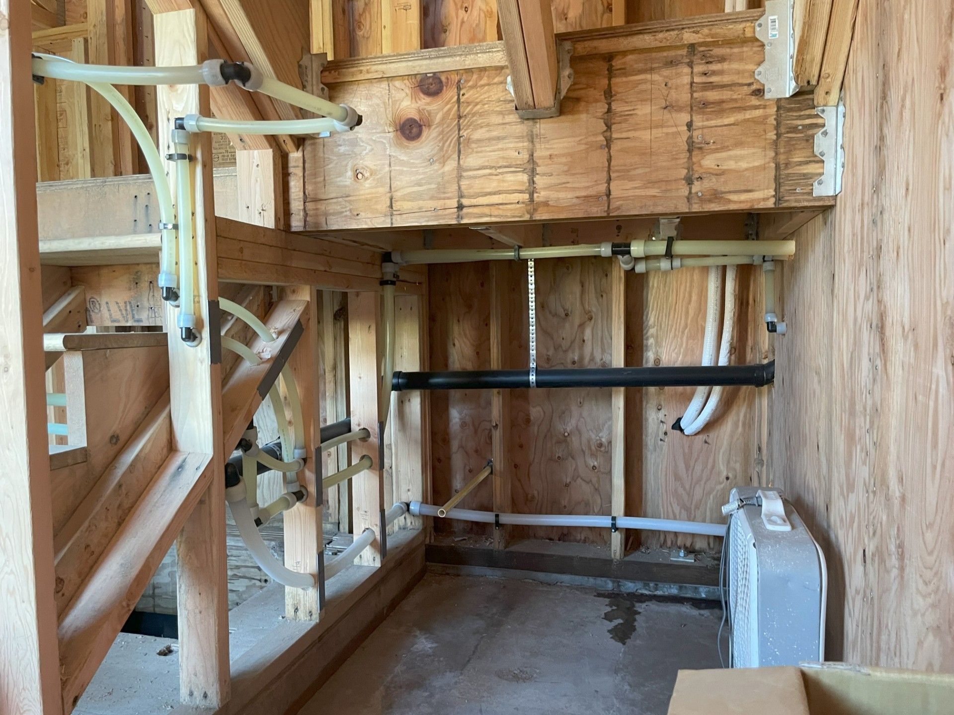 A room with a lot of drainage and plumbing pipes in it due to a rough in installation by Royal Flush Plumbing in Tacoma WA