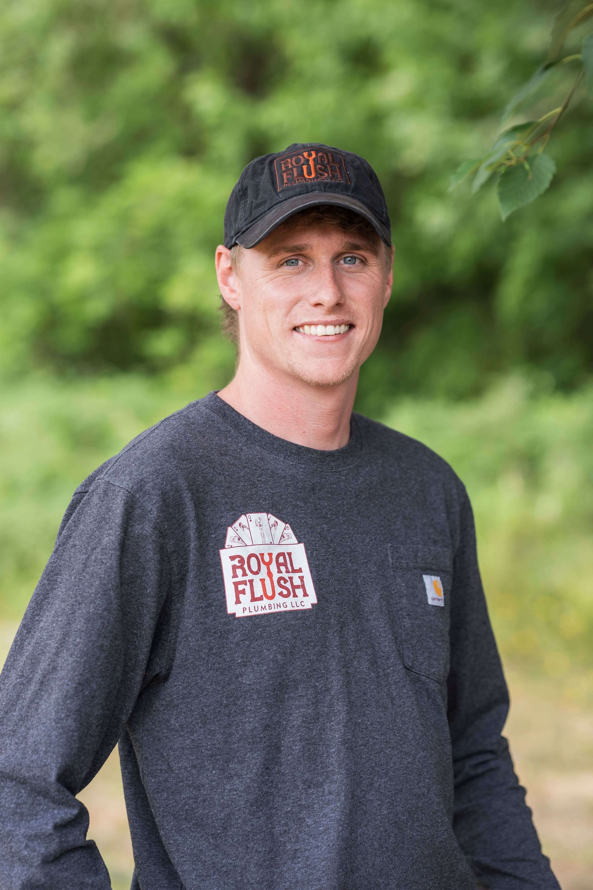 A man wearing a polo shirt and a hat is standing in front of a royal flush sign.