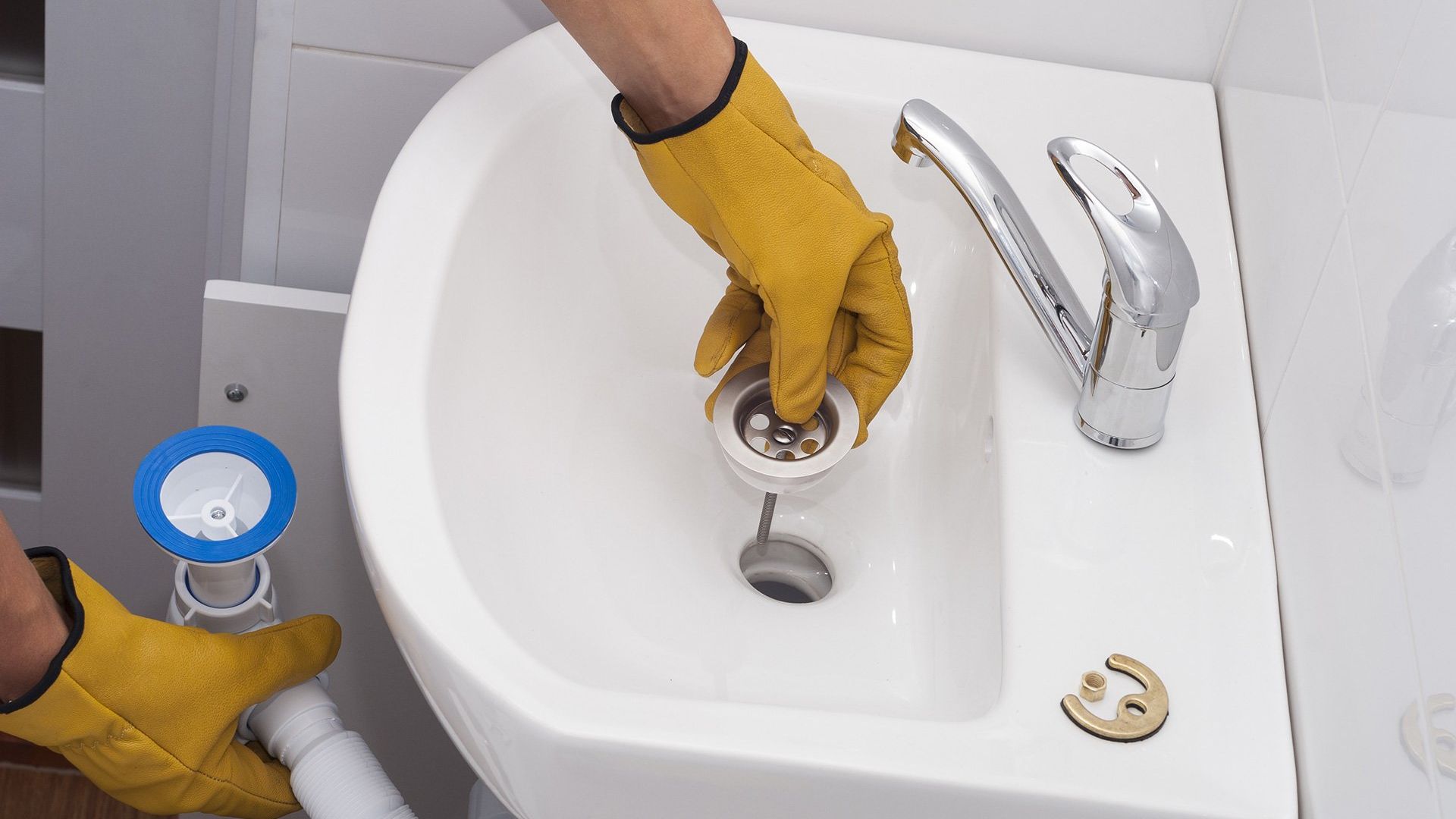 A plumber removing a clog from a bathroom sink drain