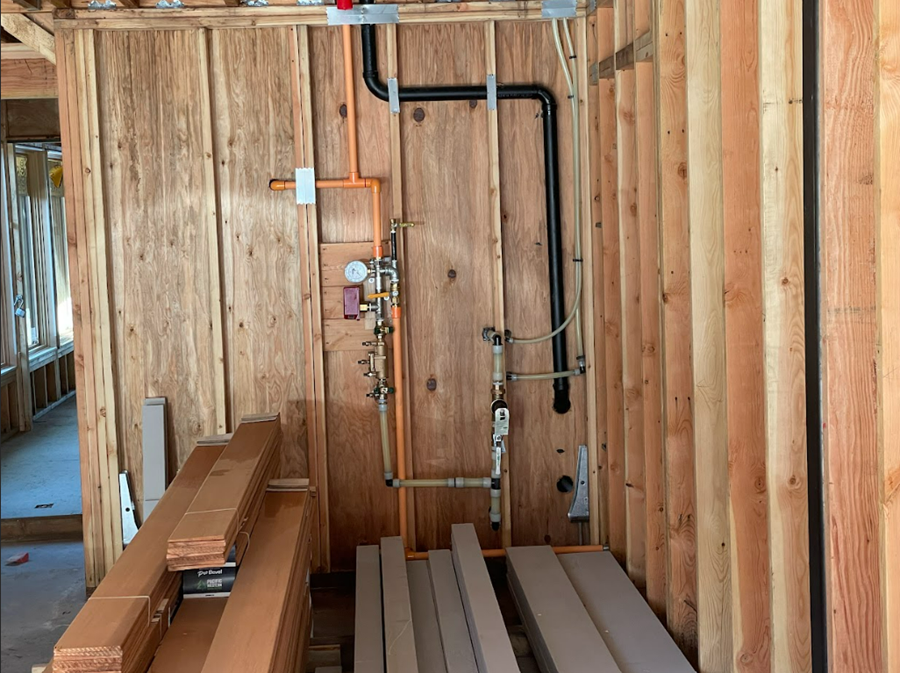 A room in a house under construction with wooden walls and rough in plumbing pipes by Royal Flush Plumbing in Tacoma WA