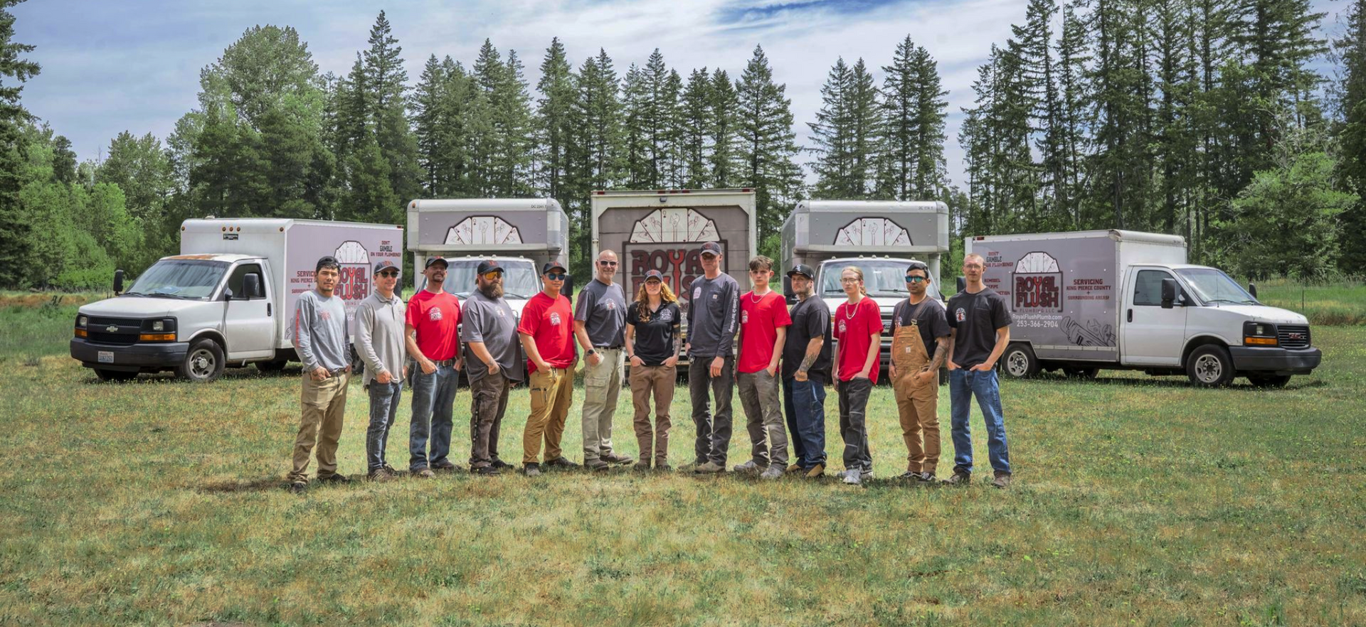 The Royal Flush Plumbing crew smiling in front of the fleet of Royal Flush Plumbing work trucks
