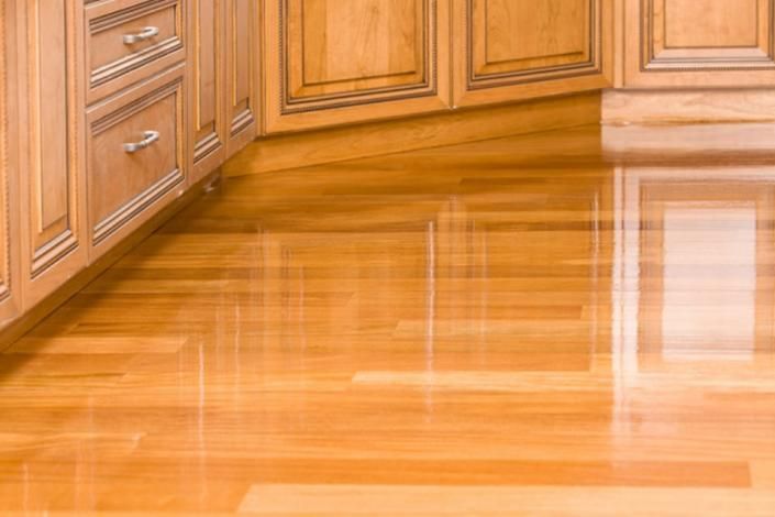 Polished wooden kitchen floor and cabinets with a glossy reflection