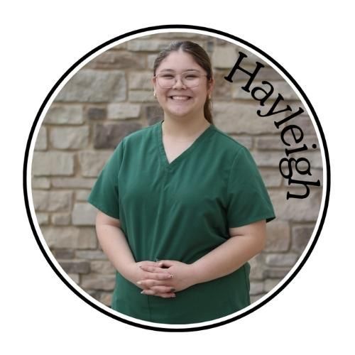 Smiling person in green scrubs before a stone wall, with the name “Hayleigh” curved beside them.