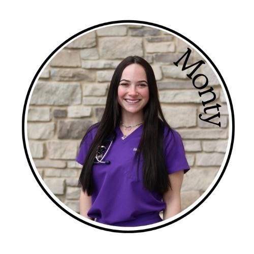 Woman in purple scrubs smiling against a stone wall, with “Monty” written along the side.