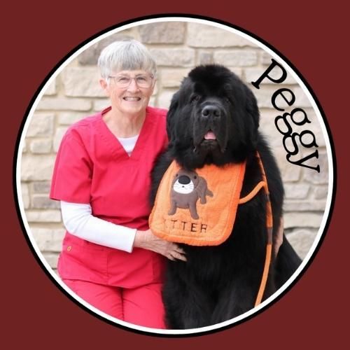 Woman with prize ribbon, bucket, and black dog in field.