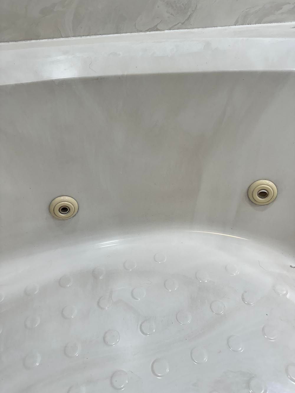 White bathtub with two jets and textured bottom.