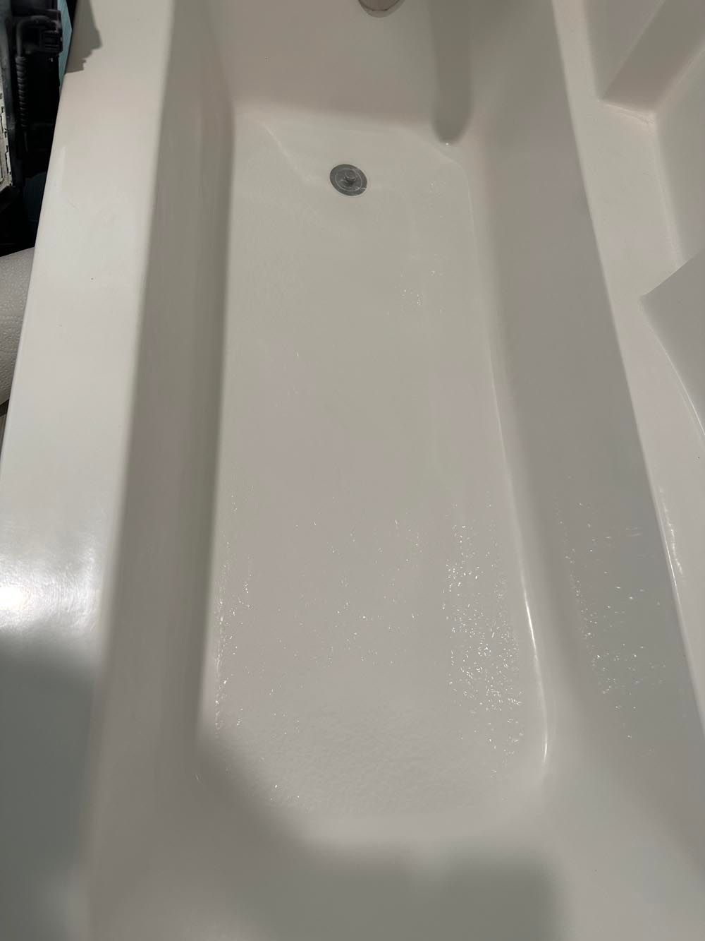White rectangular bathtub from a high angle, with a drain and faucet visible.