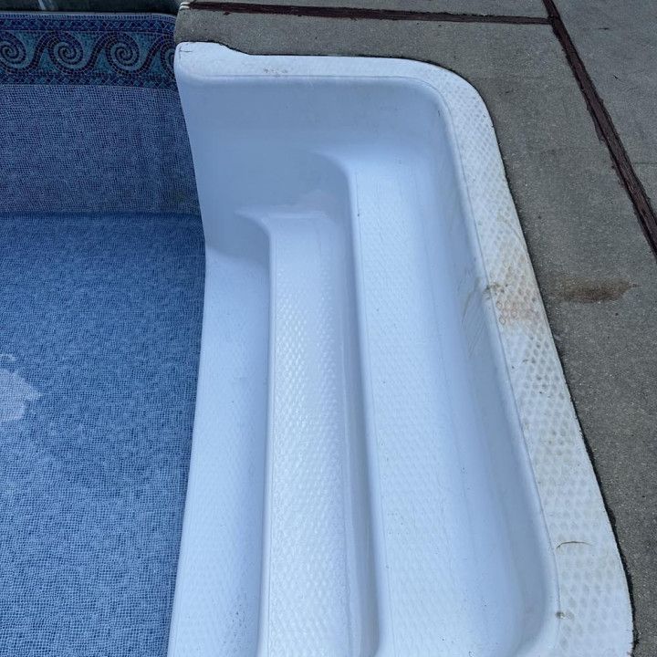 Pool steps leading into blue water, bordered by concrete.