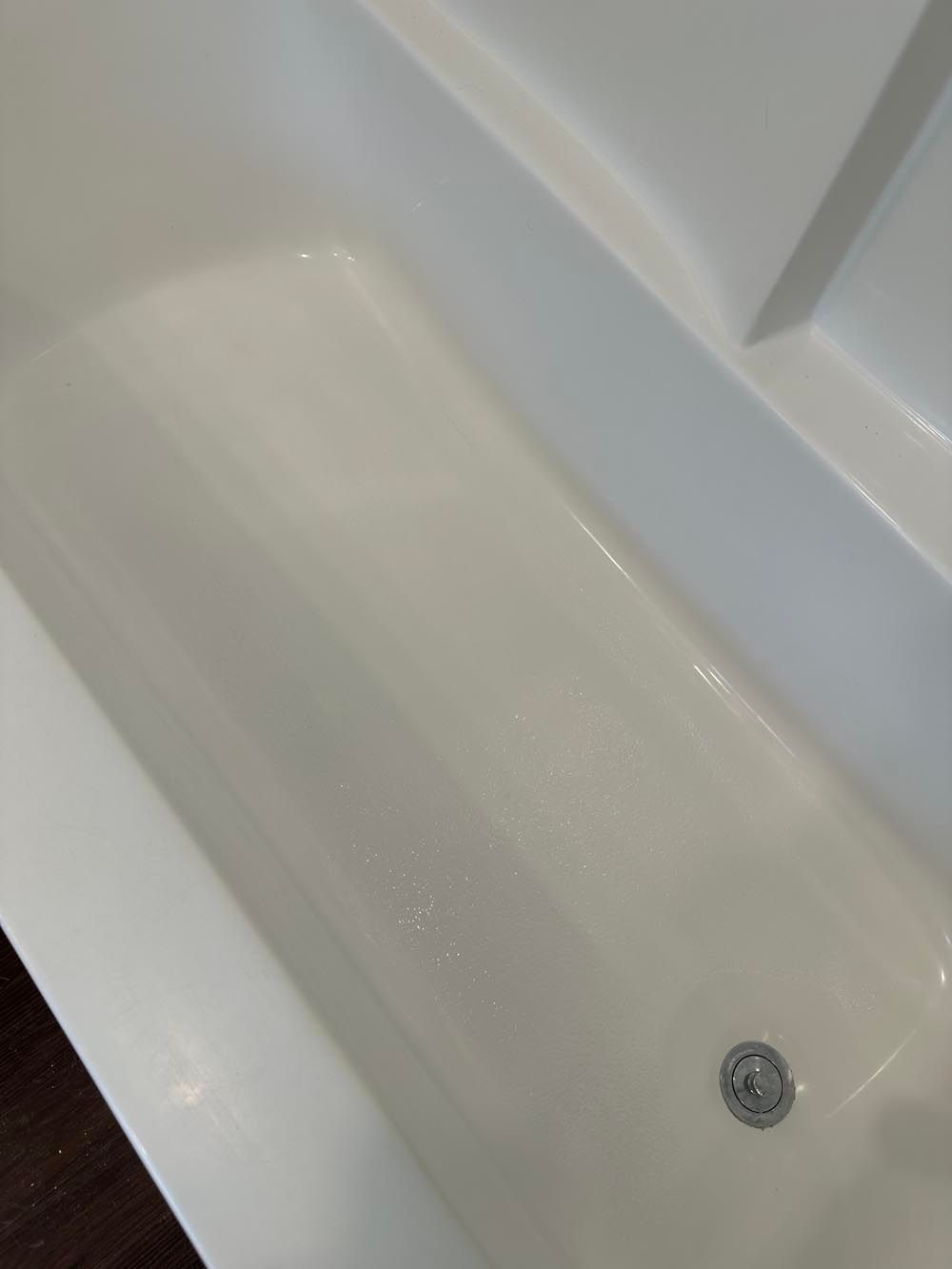 White bathtub with a drain, showing the bottom and sides.