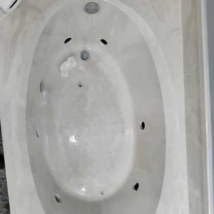 Oval, off-white jacuzzi bathtub with jets. Top-down view.